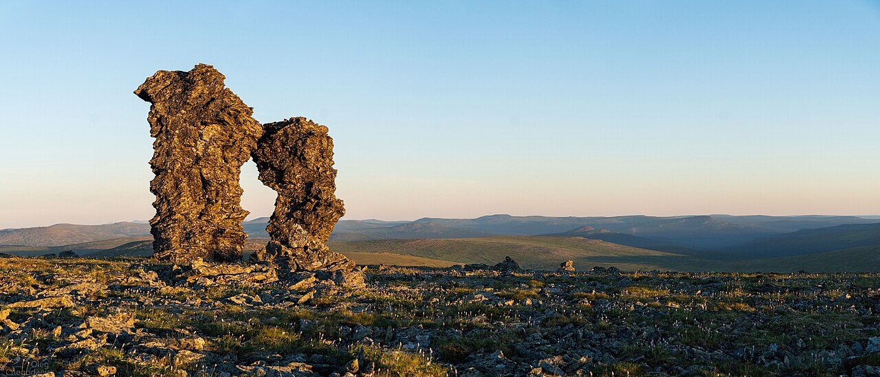 Two tall weathered rock pillars on the flat stony top of Mount Otorten, with low hills fading into the distance under a clear sky