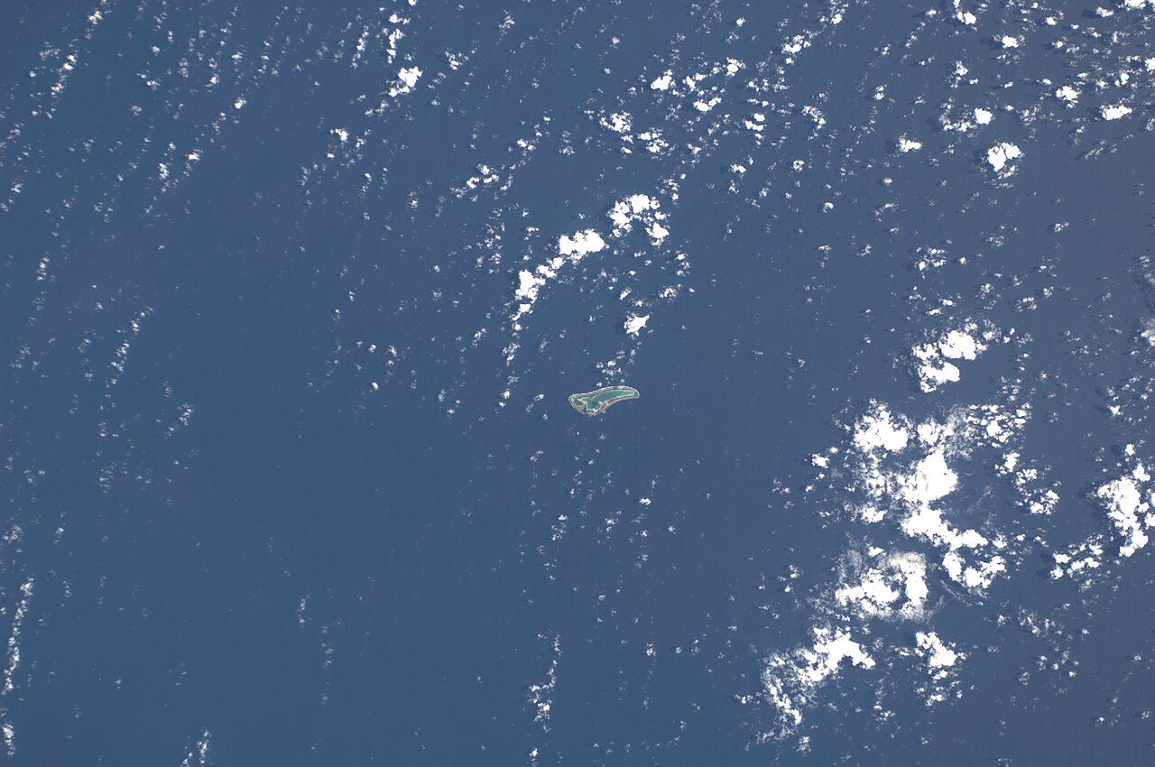 Astronaut photograph from 2008 of Gardner Island (Nikumaroro), a ring-shaped atoll in the Pacific, partly covered by cloud.