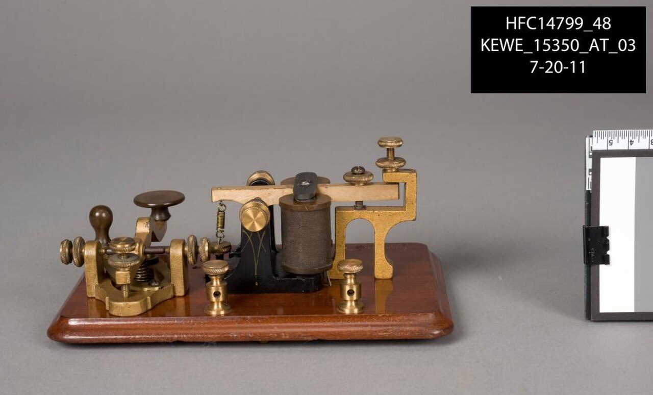 A brass telegraph key and sounder on a wooden base, made by J. H. Bunnell and Co.