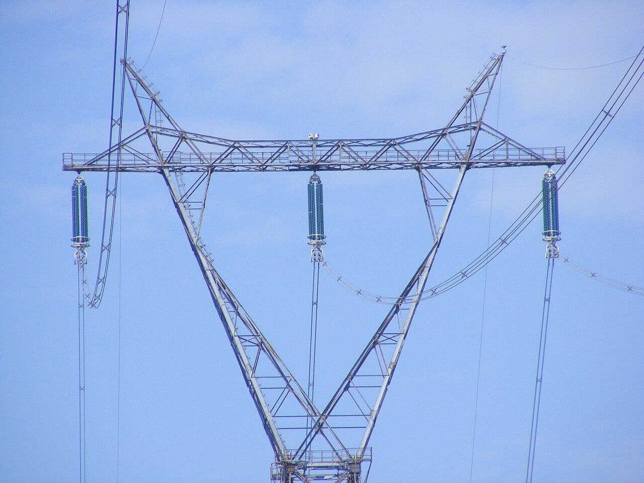 A tall steel power line tower in Quebec holding bundles of high-voltage wires against the sky