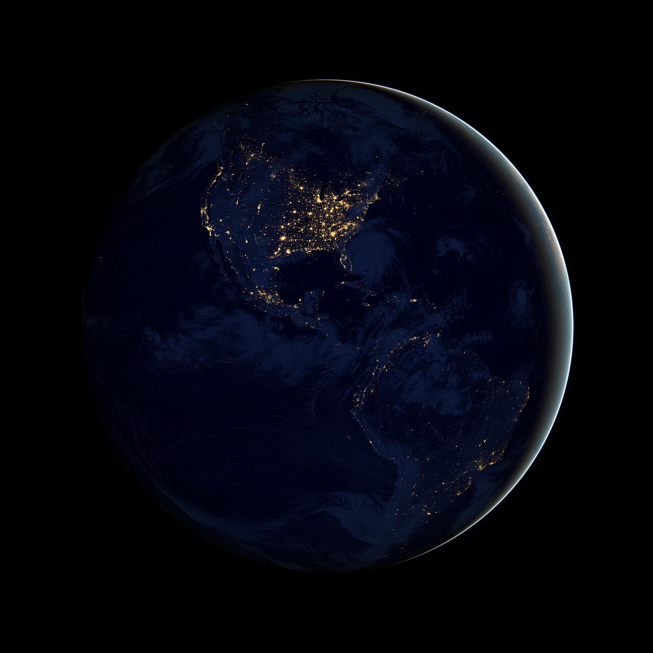 Satellite view of the Americas at night, with city lights glowing across North America